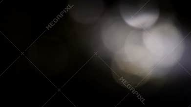 Moving colorful defocused lights dark background.