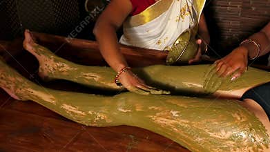 Beauticians is applying green clay on the body of