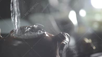 Water pouring into clay teapot