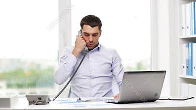 Angry businessman with laptop calling on phone