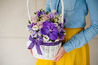 Girl holding beautiful purple bouquet of mixed flowers in basket
