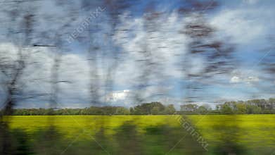 View from riding train window of coutryside landscape against cloudy sky