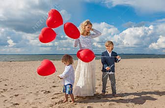 Happy family mother and two boys with red heart balloons