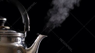 Boiling water in teapot on black background, slow motion