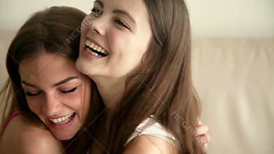 Two happy girlfriends hugging each other