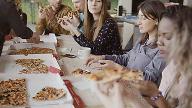 Young creative business team have meal together. Mixed race group of people eating pizza at modern office, enjoying food