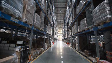 Camera moves up on shelves of cardboard boxes inside a storage warehouse