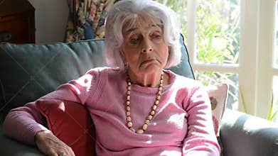 Lonely Senior Woman Sitting In Armchair At Home