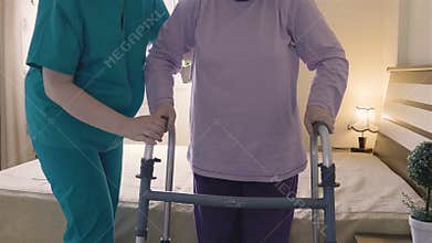 Caregiver helping senior woman getting up and walk with a walker