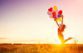 Beauty girl with colorful air balloons over sunset sky
