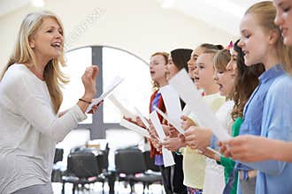 Children In Singing Group Being Encouraged By Teacher
