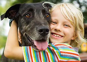 Happy young boy lovingly hugging his pet dog