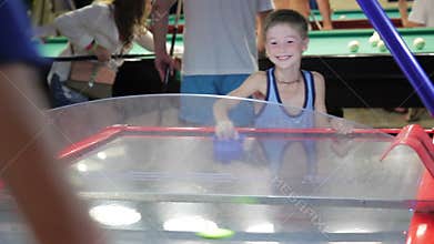 Child summer on vacation playing air hockey, joy