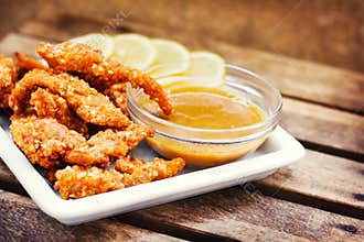 Chicken fingers served with honey-mustard dip and lemon slices