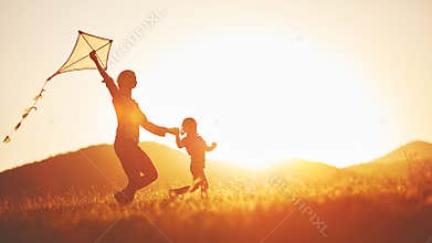 Happy family mother and child run on meadow with a kite in the s
