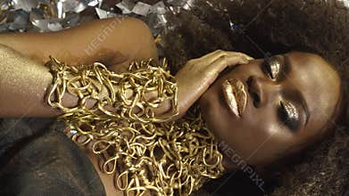 Creative surreal portrait of african american female model with gold glossy makeup Face art. Silver glossy confetti