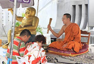 Buddhist monk blessing people ouside some buddhist temple, Thailand