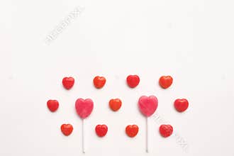 Pink Valentine`s day heart shape lollipop small red candy in cute pattern on empty white paper background. love concept. top view.