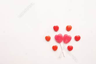 Pink Valentine`s day heart shape lollipop small red candy in cute pattern on empty white paper background. love concept. top view.