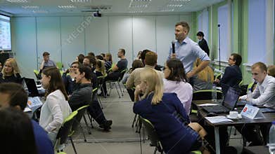 Teacher with the students look at the picture from the projector and analyze financial informationon a lesson on the