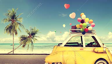 Vintage yellow car with heart colorful balloon on beach