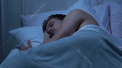 Man quietly sleeps on clean and fresh bedding, good sleep conditions, orthopedy