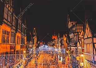 Eastgate Street Chester, UK at night with Christmas lights hanging from the impressive Tudor black and white buildings