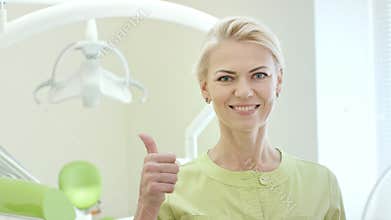 Happy dentist showing thumb up. Portrait of smiling doctor in dentist office