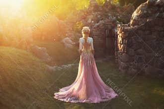 Shooting without a face, from the back. Wonderful princess with blond hair and a crown. is wearing an amazing light pink