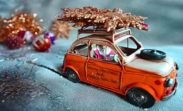Santa Claus flees with an orange car, on the snow, with Christmas decorations