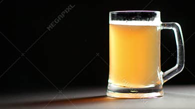 Big mug full of refreshment golden beer beverage slowly rotation isolated at black studio background