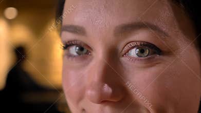 Closeup portrait of young pretty caucasian female face with eyes looking straight at camera with cheerful facial