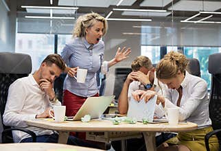 Boss yelling at employees in meeting room