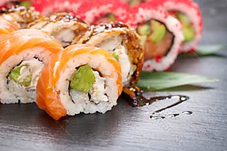 Sushi rolls closeup. Japanese food in restaurant. California sushi roll set with salmon, eel, vegetables and flying fish caviar