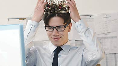 Happy businessman putting crown on head in the office