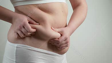 Woman in white underwear holds her belly fat.