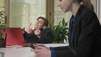 A young guy in a suit flirts with a girl in the office, throws a lasso of love, the concept of love, humor. Work in the