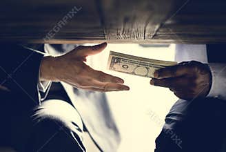 Hands passing money under table corruption bribery