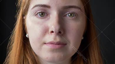 Close portrait of young serious beautiful woman face looking at camera with concerned and occupied expression, black