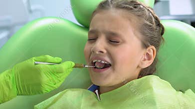 Little girl afraid of dental checkup with mouth mirror, childish fear, stress