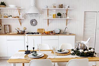 Modern new light interior of kitchen with white furniture and dining table
