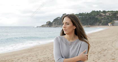Worried woman walking alone on the beach