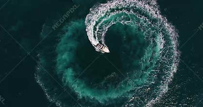 Top view figure of circle and spiral shape made with foamy speedboat traces on azure ocean water surface