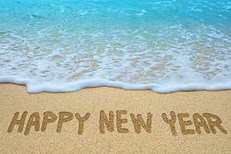 Happy new year written on sandy beach