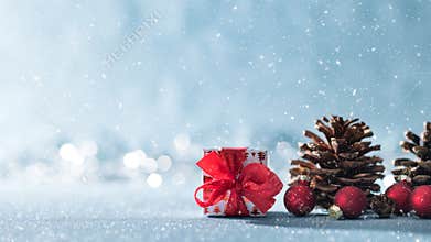 Beautiful simple Christmas background with copy space. Cute Christmas present, red ornaments and pine cones on shiny background.