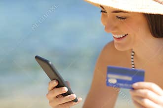 Happy tourist paying online with credit card on the beach