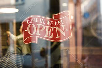 Business vintage sign that says Come in We`re Open on barber and hair salon shop window - Image of abstract blur