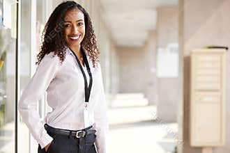 Portrait Of Smiling Female School Teacher Standing In Corridor Of College Building