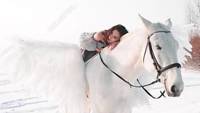 Charming pretty dark-haired lady in a long gray vintage dress with bare shoulders sits astride horse, tenderly lies on