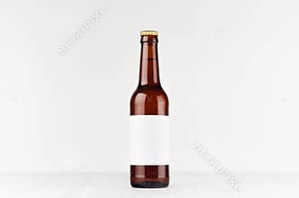 Brown longneck beer bottle 330ml with blank white label on white wooden board, mock up.